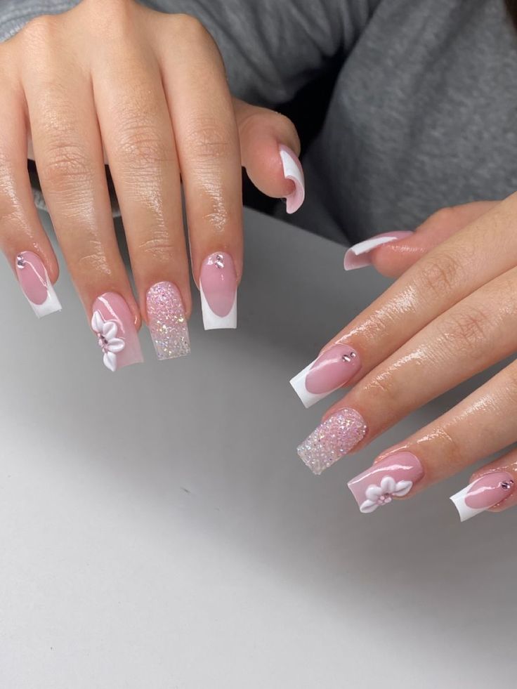 Sophisticated Elegant Nail Design with Soft Pink Base, Glossy White Tips, Sparkling Glitter, and Floral Embellishments.