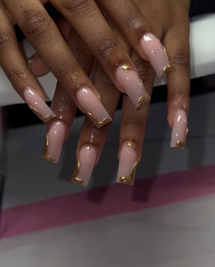 Sophisticated Nail Design: Translucent Pink Base with Bold Gold Accents