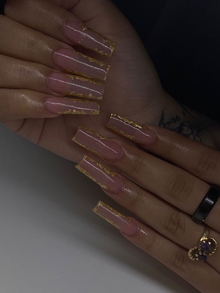 Elegant Long Acrylic Nail Design with Glossy Nude Base and Gold Foil Accents.