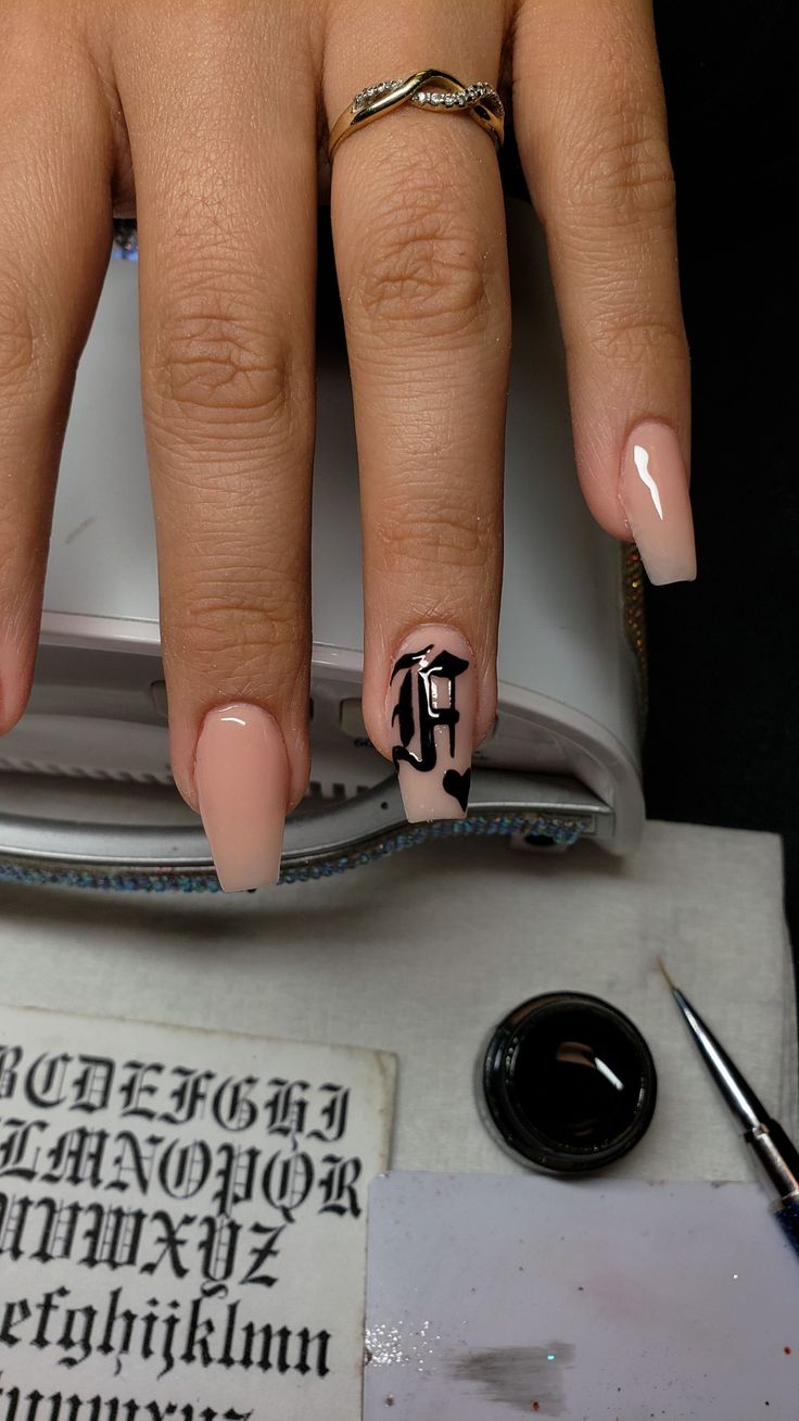 Sophisticated Nail Design: Glossy Nude Base with Bold Black Lettering