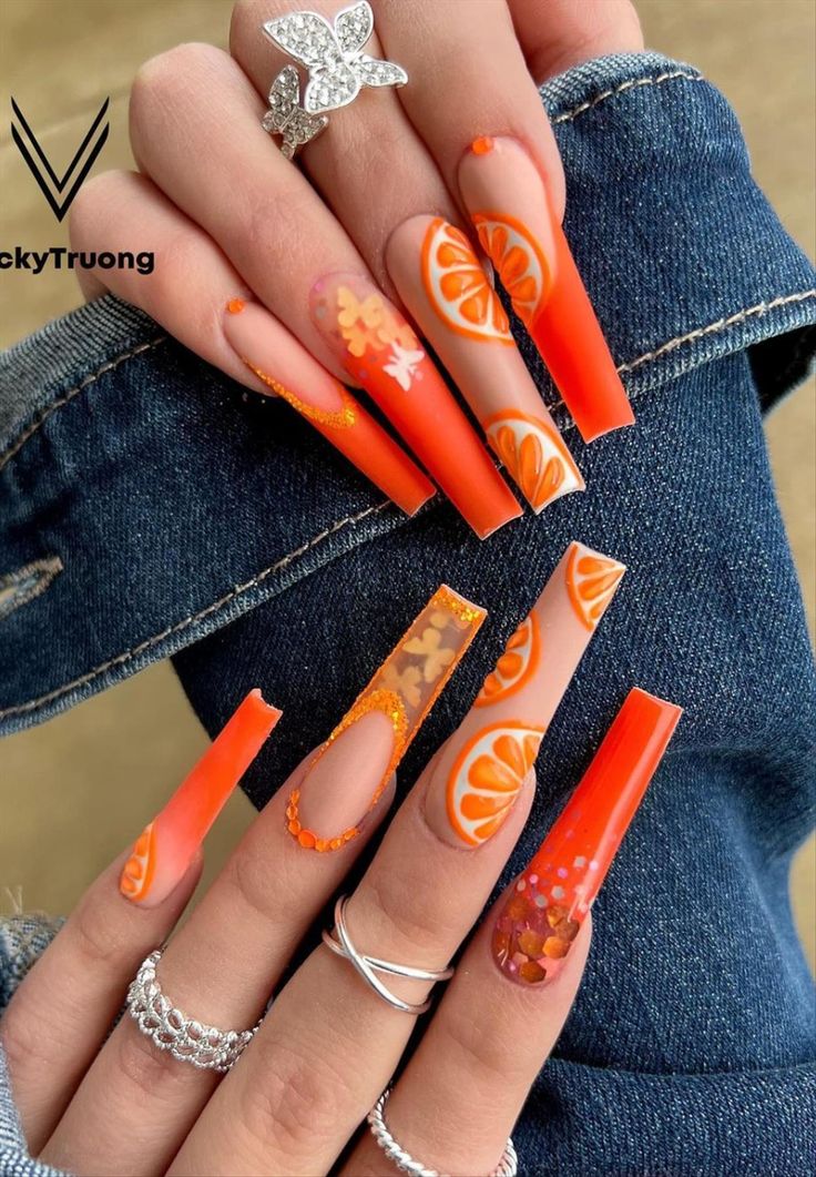 Cheerful Orange Citrus Nail Art with Playful Patterns and Sparkling Embellishments.