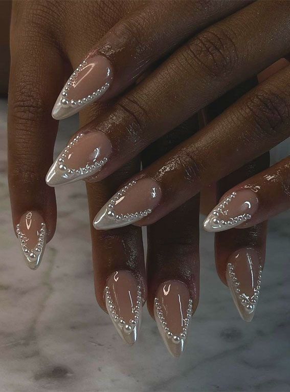 Elegant Nude and White Stiletto Nails with Sophisticated Bead Designs for a Chic Look.