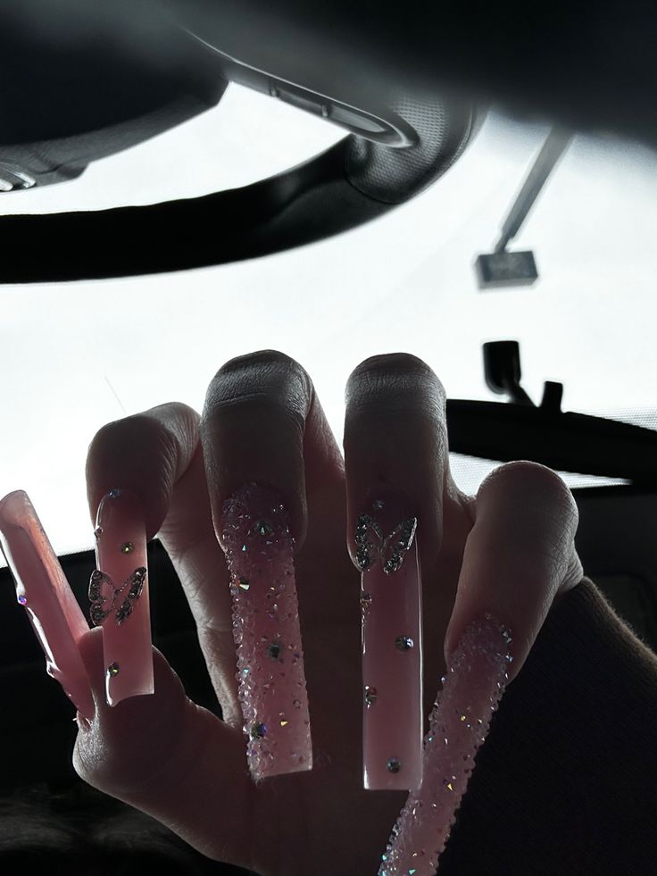 Elegant Long Pink Stiletto Nails with Butterfly Designs and Rhinestones for Trendy Statements.