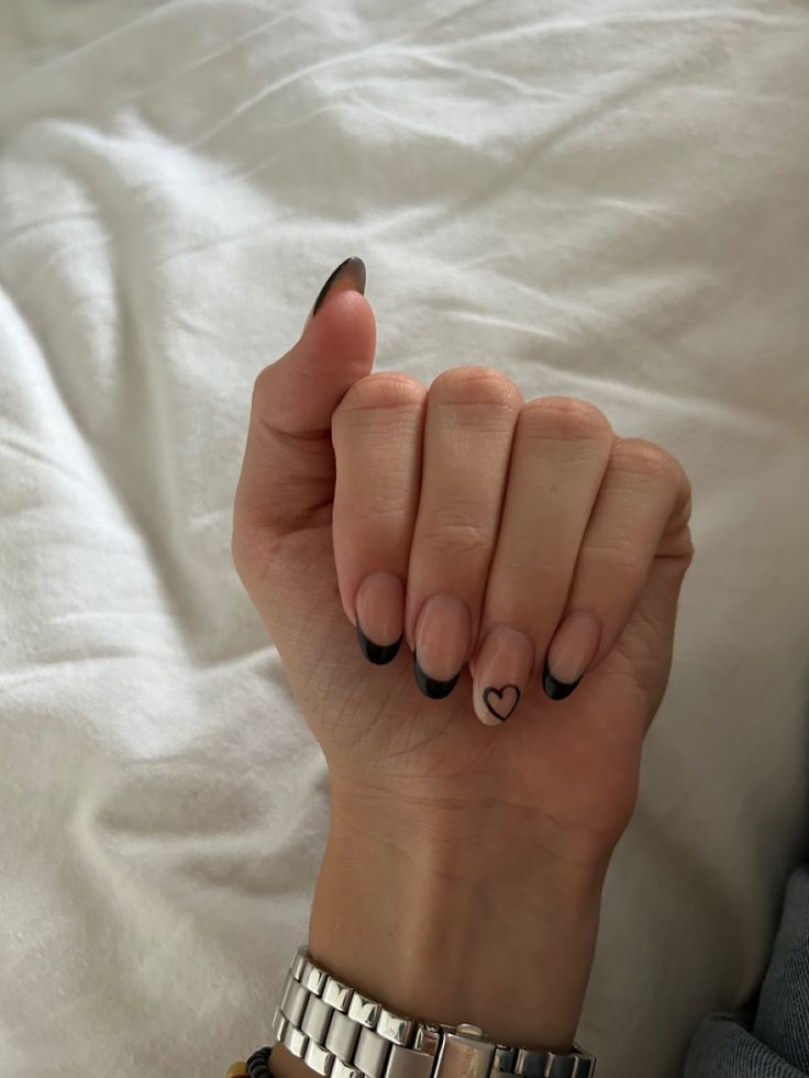 Elegant French Tip Nails with Playful Black Tips and Heart Accent Design.