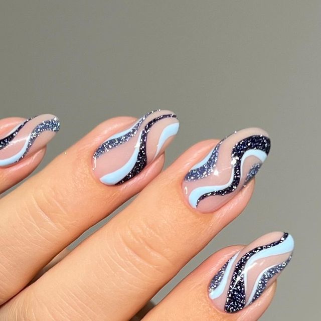 Elegant Wavy Nail Design in Soft Blue and Nude with Glossy Black Lines and Glitter.