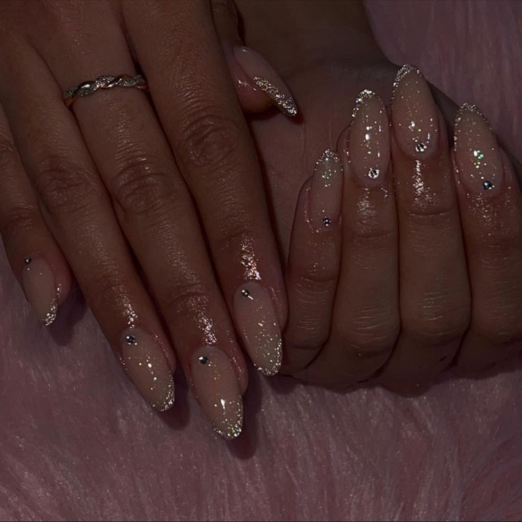 Chic and Glamorous Nude Nail Design with Glitter Tips and Rhinestones.