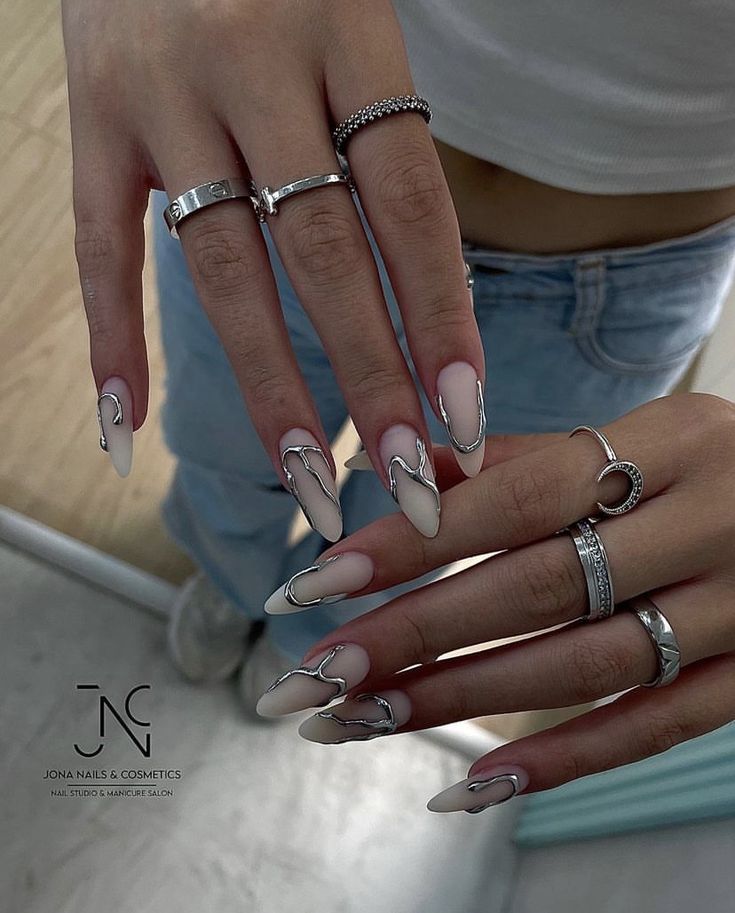 Chic Almond-Shaped Nails with Nude Polish and Silver Accents for Sophisticated Style.