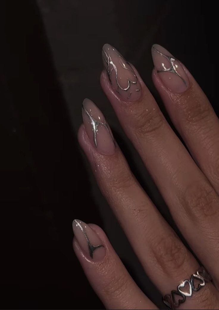 Sophisticated Whimsical Nail Design: Soft Nude Base with Silver Heart and Wave Patterns.