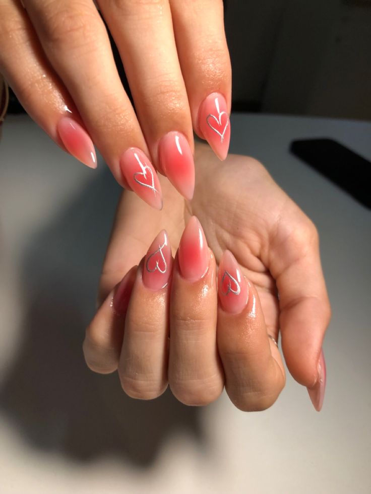 Chic Pink Ombre Nails with White Heart Accents for a Romantic Touch.