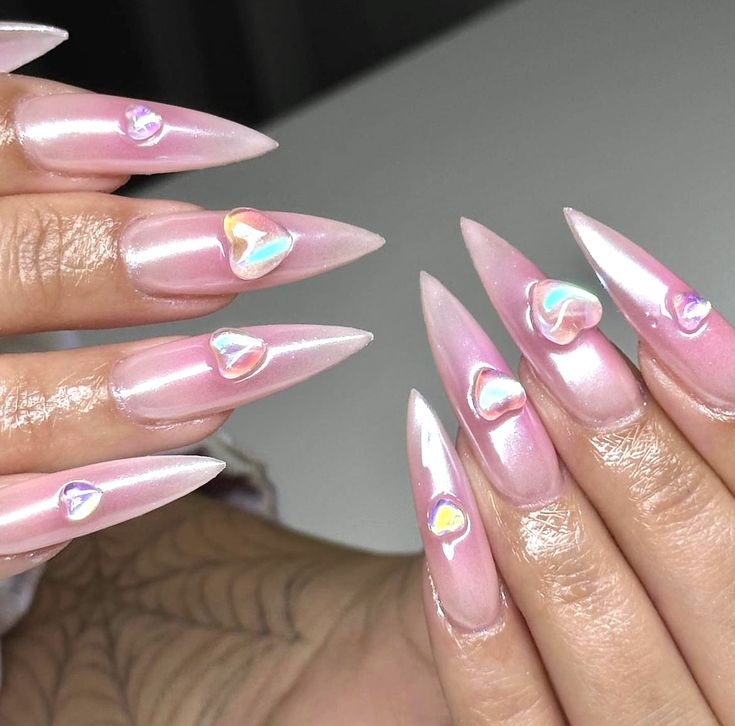 Chic Stiletto Nails with Soft Pink Base and Iridescent Heart Embellishments