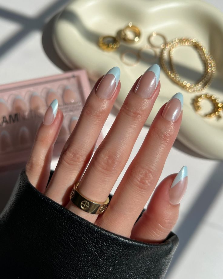 Chic Nude and Soft Blue French Tip Nail Design with Tapered Shape and Gold Jewelry Accents.