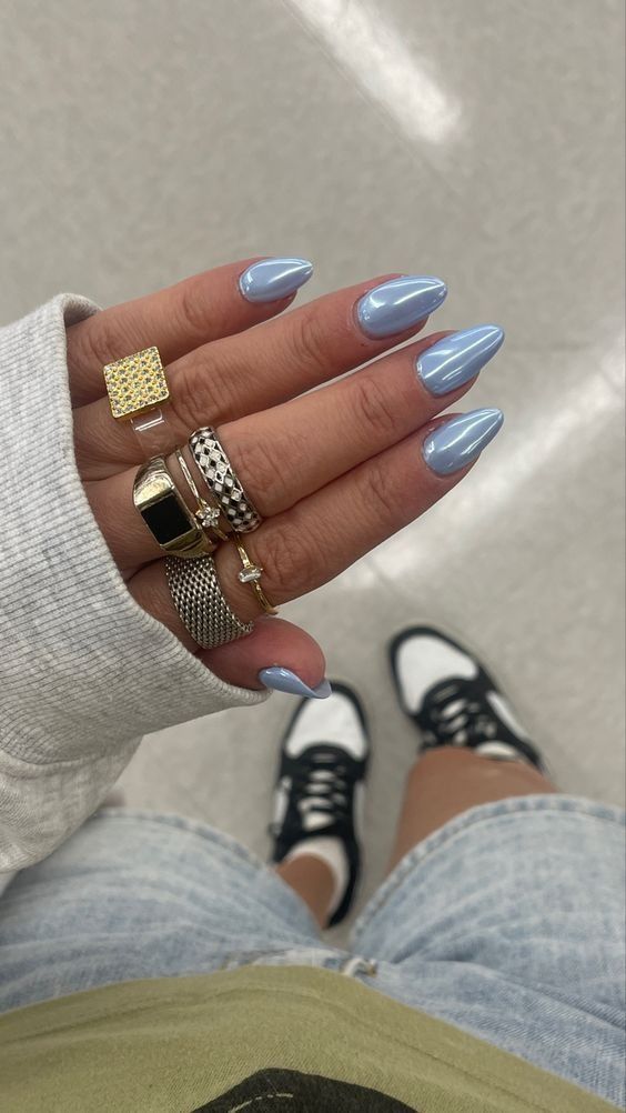 Chic Pastel Blue Long Almond Nails Enhanced by Trendy Rings for a Fashionable Look.