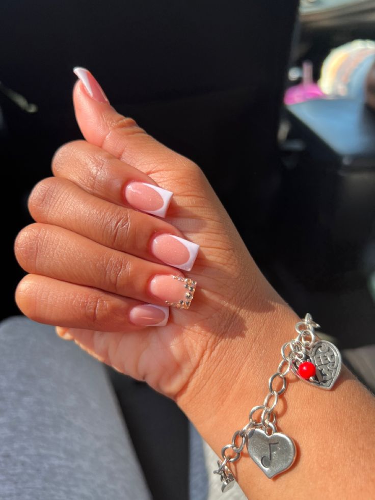 Chic French Manicure with Sparkling Accent and Silver Bracelet.