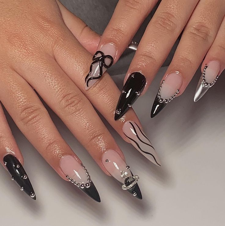 Chic Black and Nude Nail Design with Wavy Lines, Metallic Accents, and Jewel Embellishments.