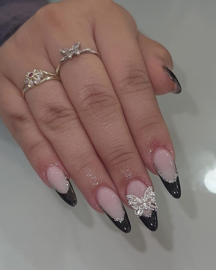 Elegant Stiletto Nail Design in Monochrome with Silver Butterfly Accents and Dainty Rings.