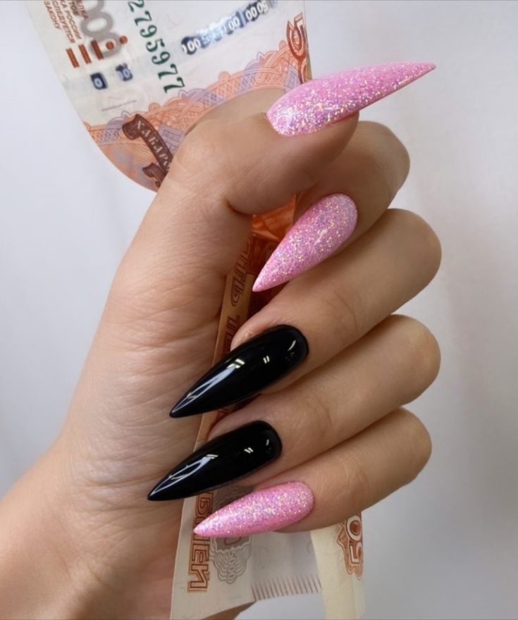 Bold Stiletto Nail Design: Glossy Black Meets Sparkling Pink for a Fashionable Statement.