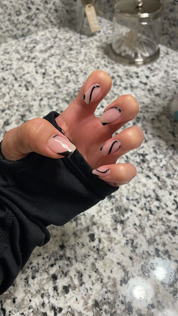 Chic Nail Design with Nude Base, Striking Black Swirls, and Elegant French Tips.