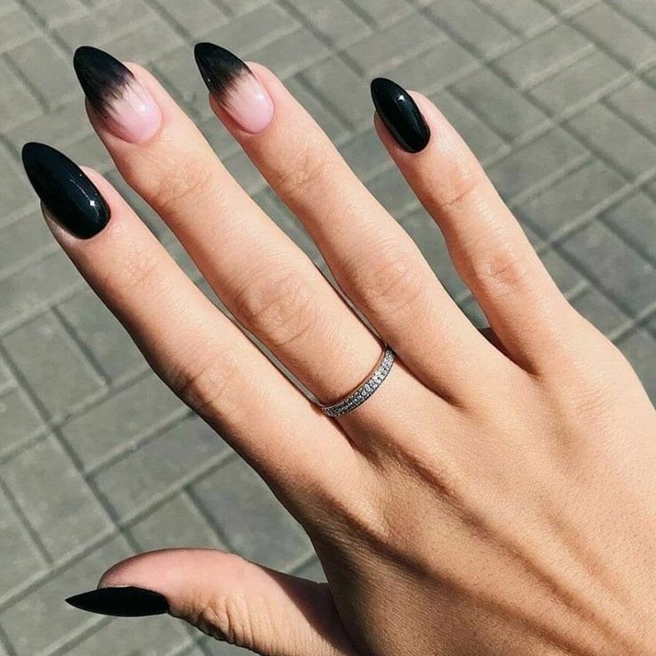 Elegant Ombre Nail Design: Striking Black and Nude Blend with Almond Shape and Silver Accents.