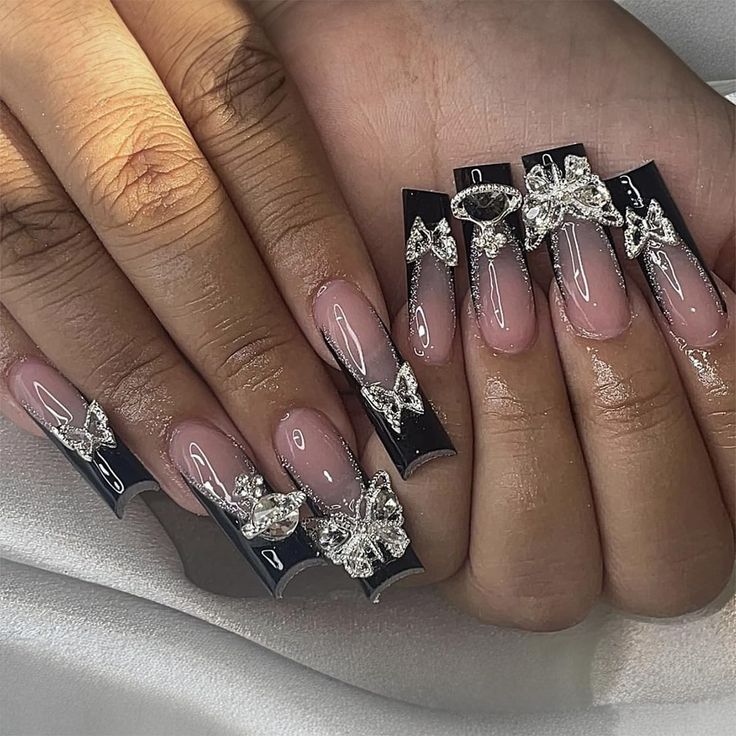 Elegant Nude and Black Nail Design with Striking Silver Embellishments.