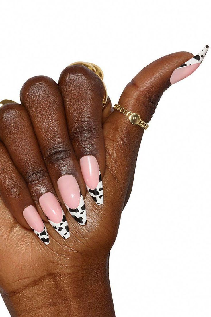 Chic Cow Print Almond Nails with Pink and Black Accents, Enhanced by Minimalist Gold Accessories.