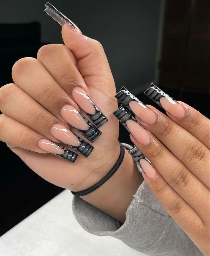 Sophisticated Nude and Black Almond-Shaped Nail Design with Unique Clip Accent.