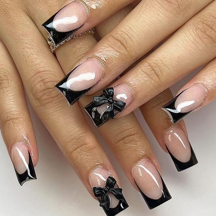 Chic Black and Nude Nail Design with Glossy Tips and Playful Bow Accents.