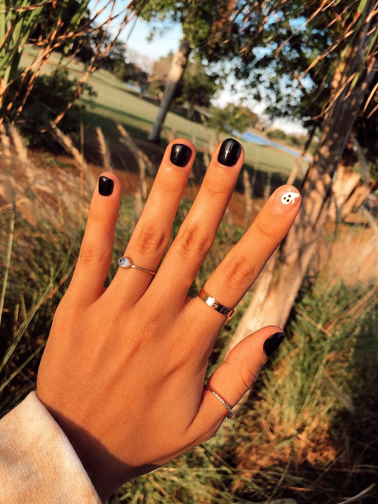 Chic Black and White Nail Design with Playful Accent and Delicate Rings