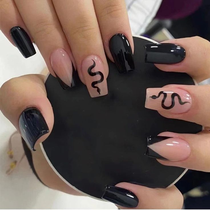 Chic Black and Nude Nail Design with Whimsical Snake Pattern Accent.