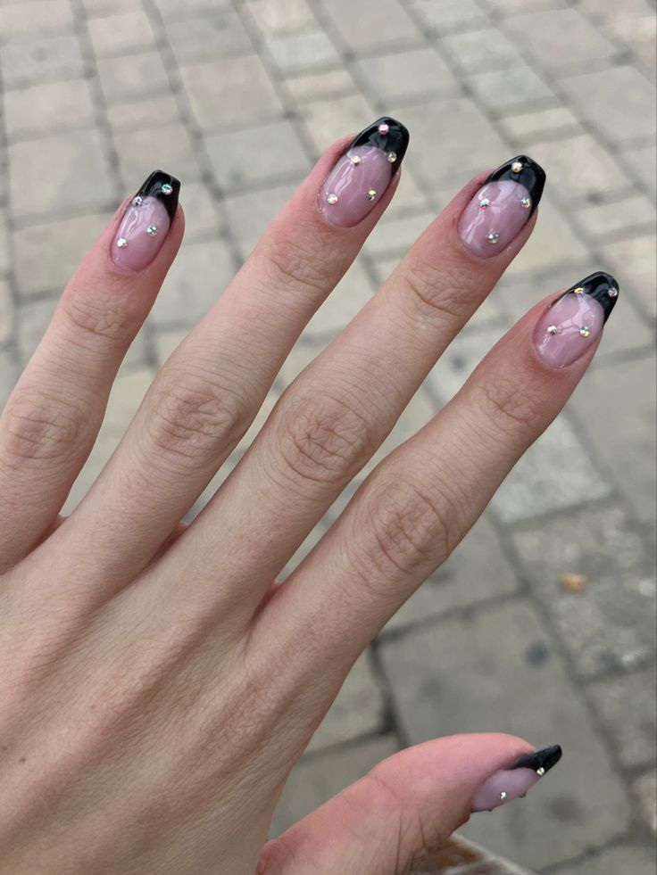 Chic French Tip Nail Design: Glossy Black Tips with Transparent Pink Base and Gold Accents.