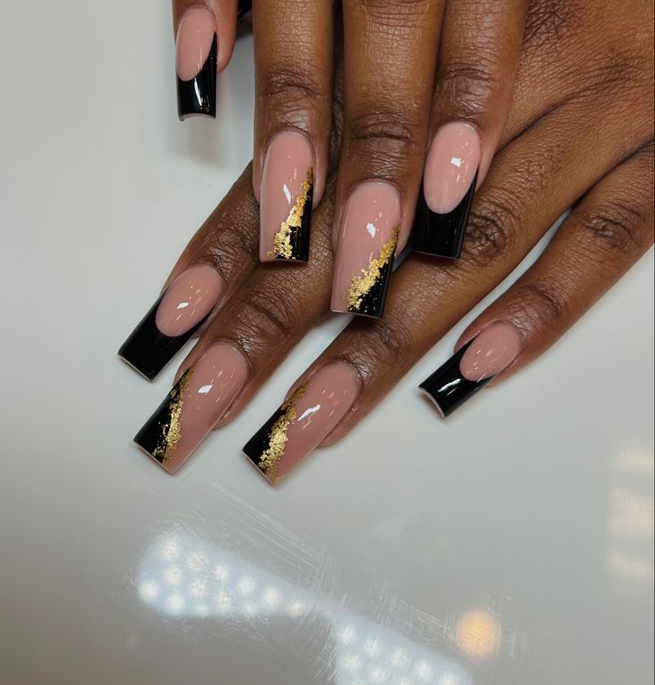 Chic Nude and Black Nail Design with Gold Accents: A Modern Take on Classic French Tips.