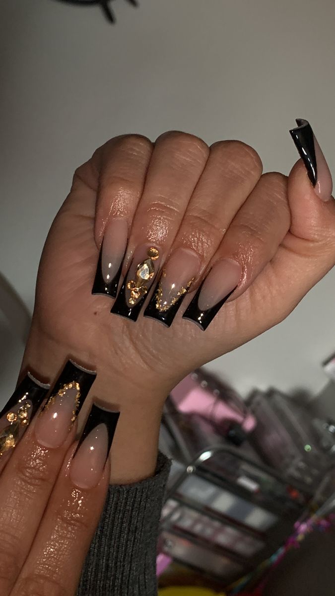 Luxurious Nude and Black Acrylic Nails with Gold and Crystal Accents.