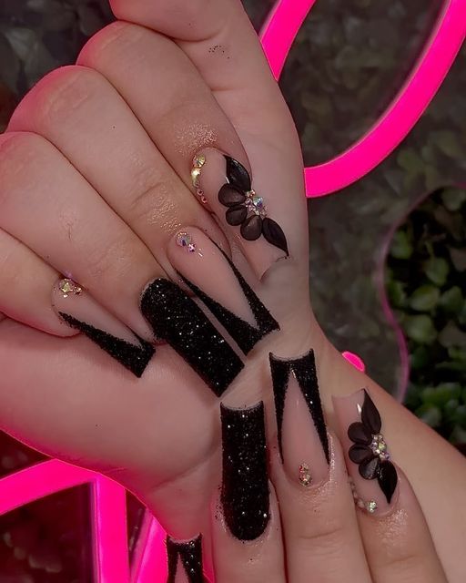 Elegant Black Nail Design with Matte, Glitter, Floral Accents, and Dramatic Tips.