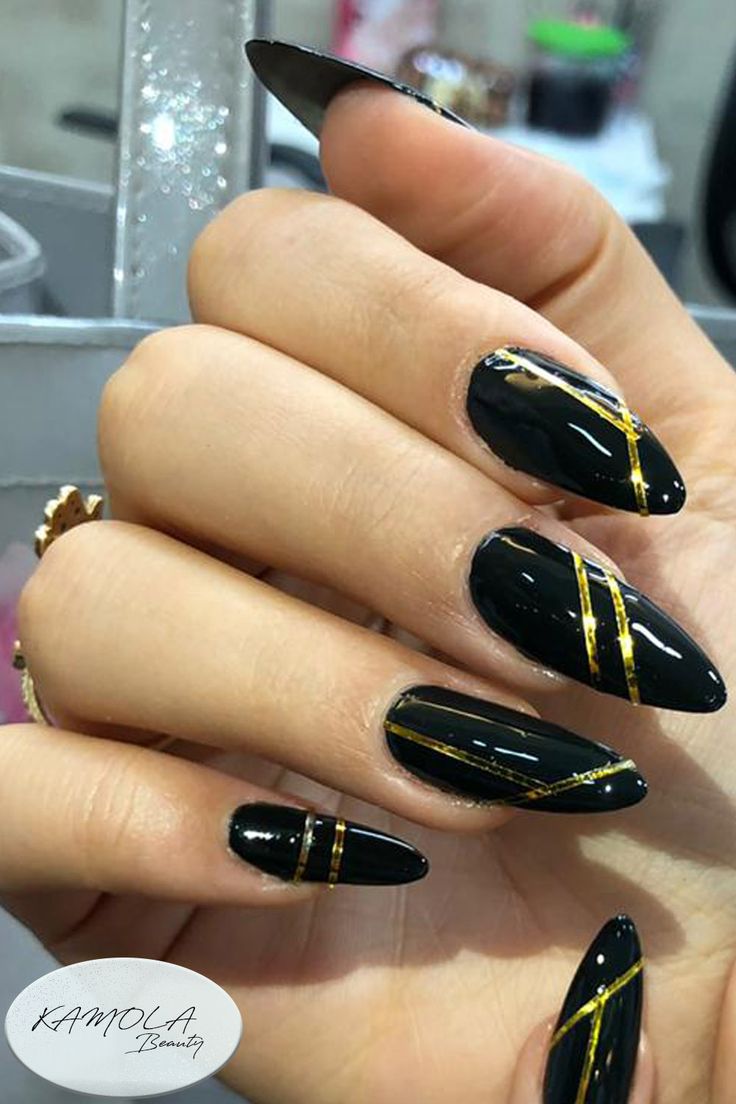 Sophisticated Black Almond Nails with Gold Geometric Accents.