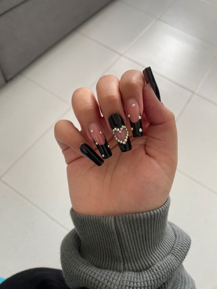 Glamorous Black and Nude Heart-Adorned Nail Design with Tapered Tips.