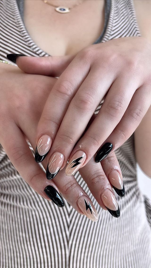 Chic Almond-Shaped Nail Design: Nude and Black with Bold French Tips and Lightning Bolt Accents.