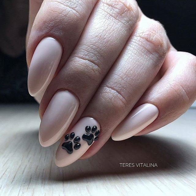 Chic Almond-Shaped Nude Nails with Playful Black Paw Print Accent for Animal Lovers.