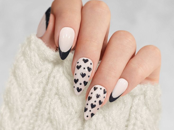 Chic Heart-Themed Nail Design in Nude and Black with Trendy Pointed Shape.