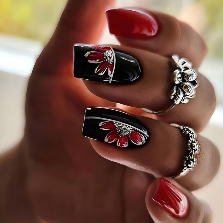 Stunning Nail Design: Glossy Black with Floral Patterns and Vibrant Red Accents.