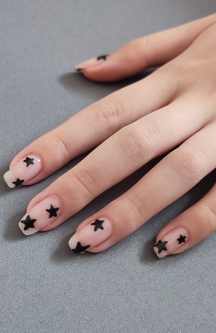 Trendy Nude and Black Star Accented Nail Design: Playful Elegance for Any Occasion.