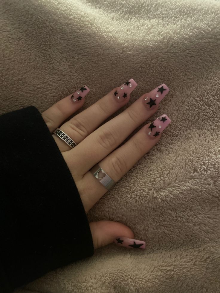 Playful Pastel Pink Nail Design with Bold Black Star Accents for Trendy Elegance.