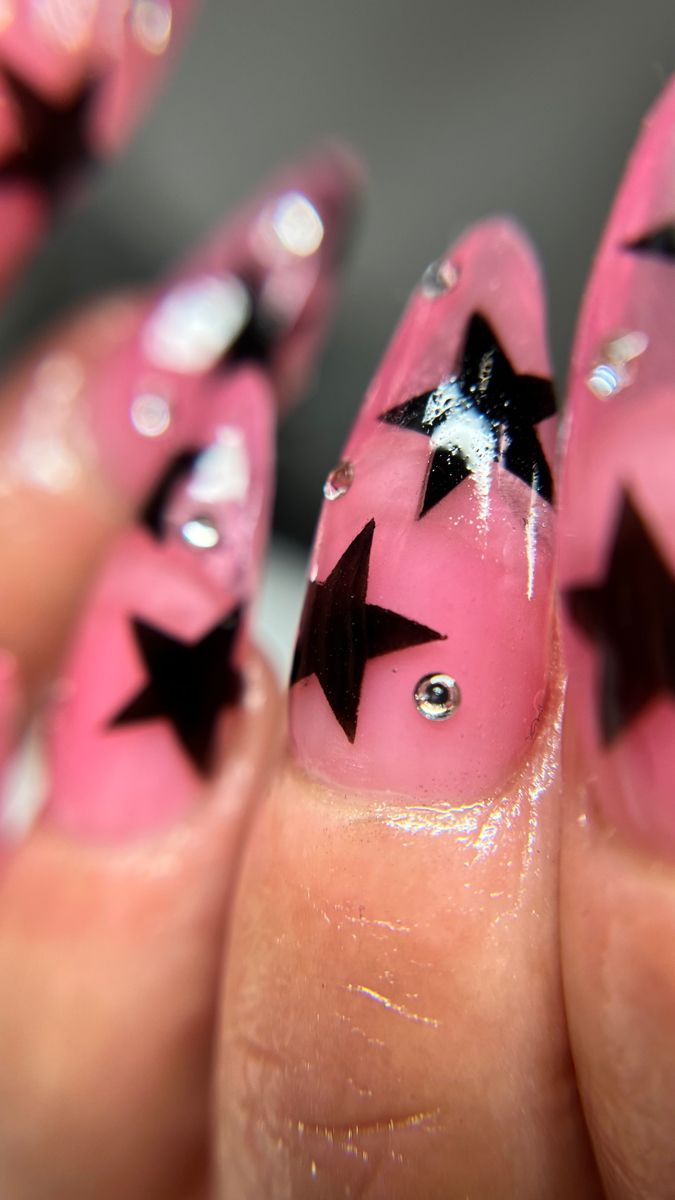 Playful Pink and Black Nail Design with Bold Stars and Sparkling Gems.