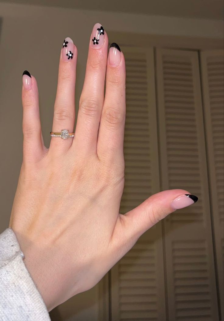 Chic Nude and Black Tipped Nail Design with Floral Accents for Versatile Elegance.