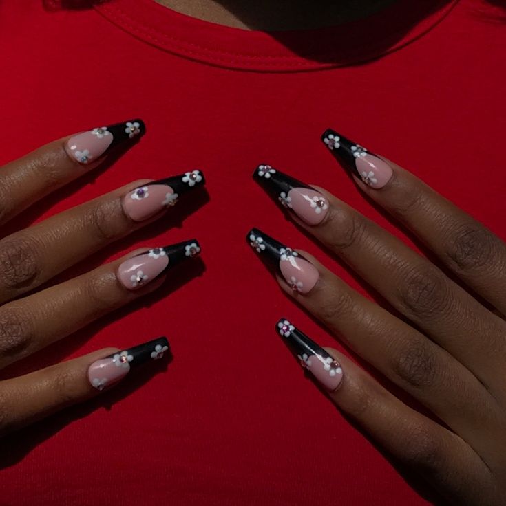 Elegant Nail Design: Bold Black Tips, Soft Nude Bases, and Delicate Floral Accents.