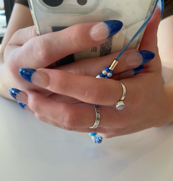 Chic Blue Ombre Nails: Eye-Catching Blend of Deep Blue Tips and Light Nude Base with Accessories.