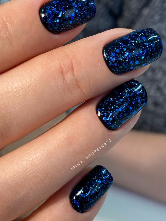 Mesmerizing Cosmic-Inspired Blue and Black Nail Design with Shimmering Finish.