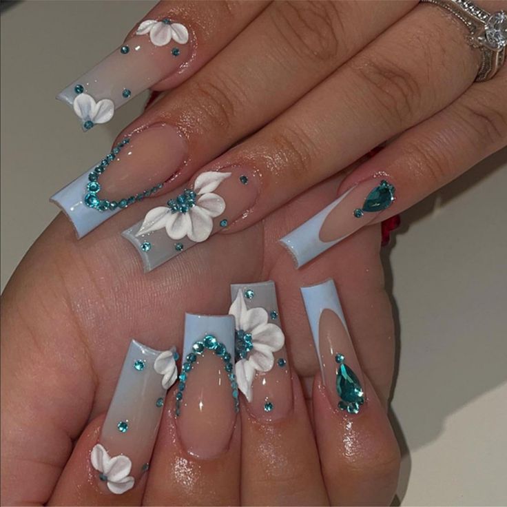 Whimsical Soft Blue Nail Design with Delicate White Flowers and Shimmering Turquoise Gems.