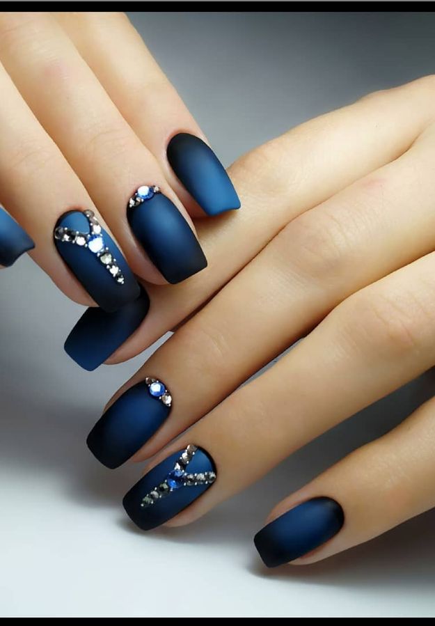 Elegant Matte Blue Nail Design with Intricate Embellishments and Glittering Gems.