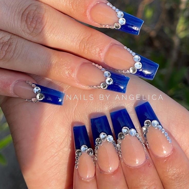 Chic and Modern Nail Design with Bold Blue Tips, Elegant Nude Bases, and Sparkling Rhinestones.