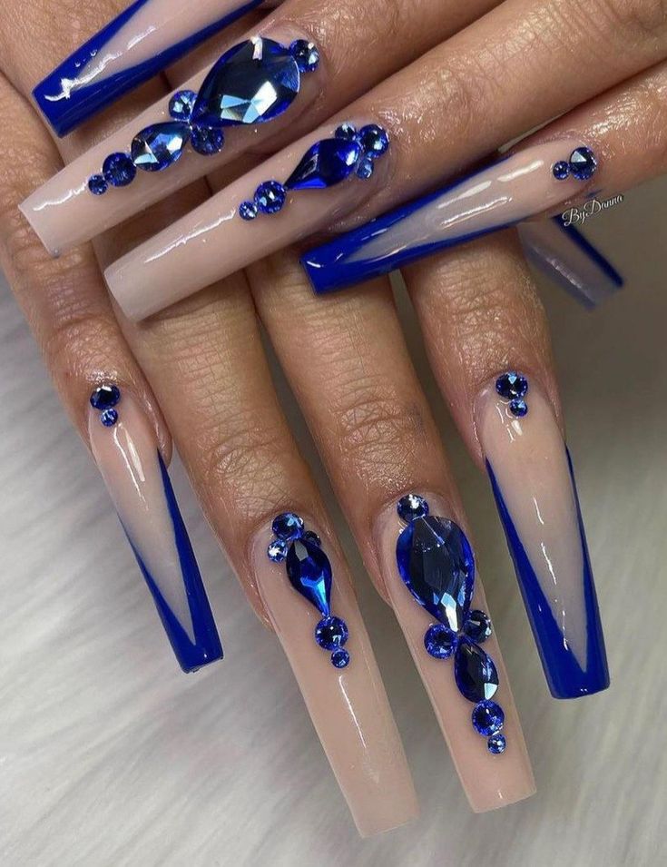 Luxurious Nail Design: Nude and Deep Blue with Rhinestones and Gem Accents.