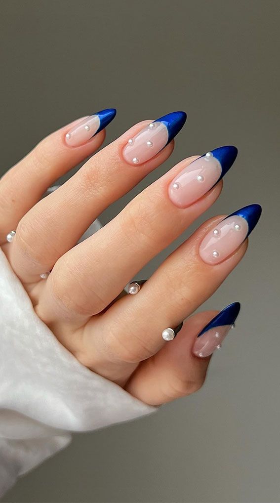 Sophisticated Nude and Deep Blue Nail Design with Glossy Tips and Pearl Accents.